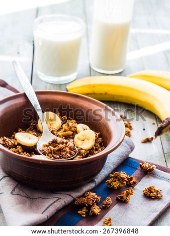 granola with bananas, nuts, figs and honey, milk, healthy breakfast on a gray background