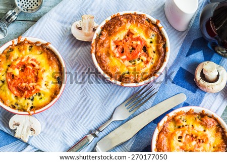 Baked mushroom julienne with tomato and cheese in red pots, top view, lunch on gray board