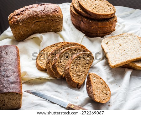 assortment of baked bread, slices of rye bread, bran cereal, rustic on a white linen tablecloth