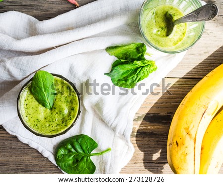 Vitamin green smoothie with spinach leaves, banana and peanut milk, clean eating,on gray wooden background