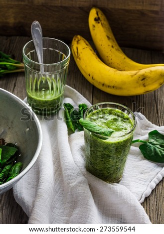 green smoothie with spinach leaves, banana in a glass on a gray wooden background, rustic