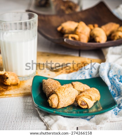 bagels biscuits from short pastry stuffed with condensed milk in a wooden plate, a glass of milk, dessert on white background
