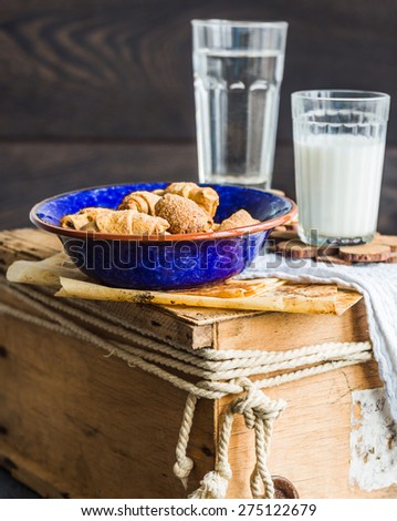 bagels biscuits from a short pastry with filling, milk, in the blue plate sweet pastries on a wooden background