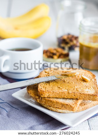 crispy toast with peanut butter, bananas, coffee, breakfast on a wooden background
