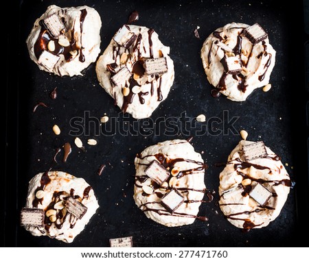 meringue with chocolate and caramel topping, nuts and souffle, dessert on a dark background