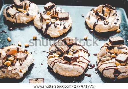 meringue with chocolate and caramel topping, nuts and souffle, dessert on a dark background