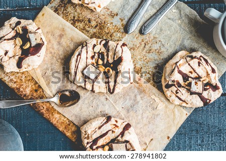 vanilla meringue with chocolate, caramel topping and nuts, sweet cake, a cup of tea on a blue background, top view