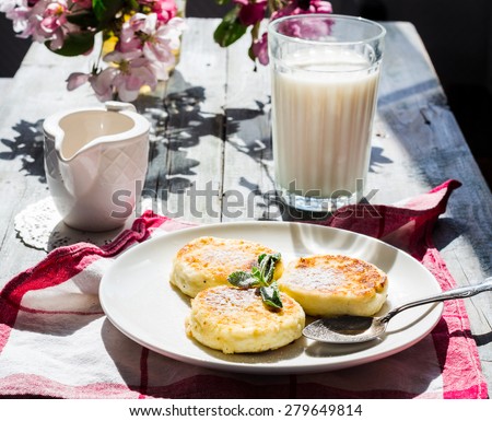 cottage cheese pancakes with mint and powdered sugar, flowers, a glass of milk and honey, breakfast