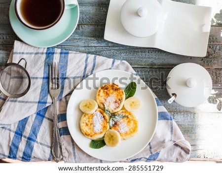cottage cheese pancakes with banana, powdered sugar and fresh mint, blue background, healthy breakfast