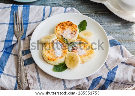 cottage cheese pancakes with banana, powdered sugar and fresh mint, blue background, healthy breakfast