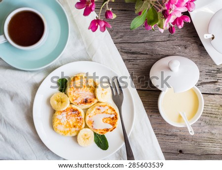 Homemade cottage cheese pancakes  with banana, condensed milk and fresh mint, gray wooden background, breakfast,top view
