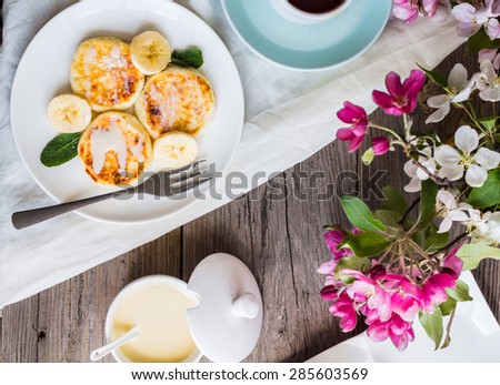 Homemade cottage cheese pancakes  with banana, condensed milk and fresh mint, gray wooden background, breakfast,top view