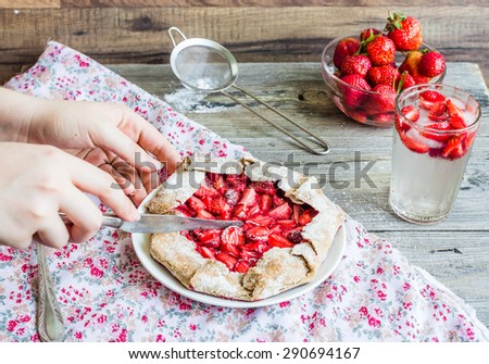 cut with a knife into pieces of rye biscuit with fresh strawberries, cake, hands,\
summer dessert