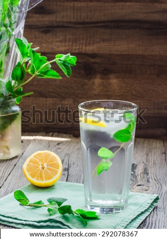 lemonade with ice, lemon slices and fresh mint in a glass, rustic background, selective focus