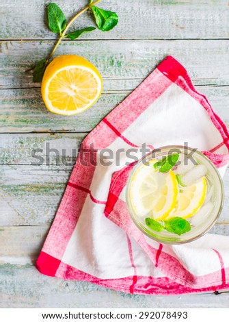 lemonade with ice, lemon slices and fresh mint in a glass, blue wood background, top view