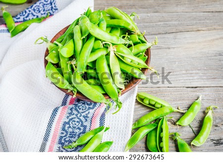 young green peas in the pod, earthenware dish, rustic background, raw,\clean eating, selective focus