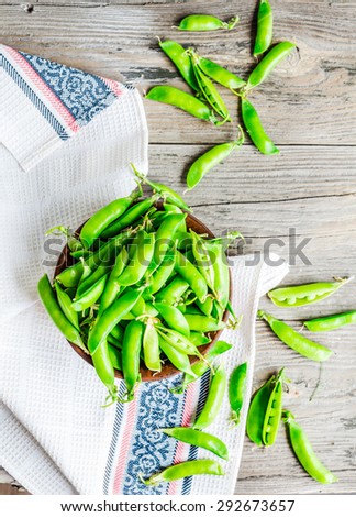 young green peas in the pod, earthenware dish, rustic background, raw,\clean eating, top view
