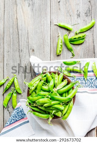 young green peas in the pod, earthenware dish, rustic background, raw,\
clean eating, top view