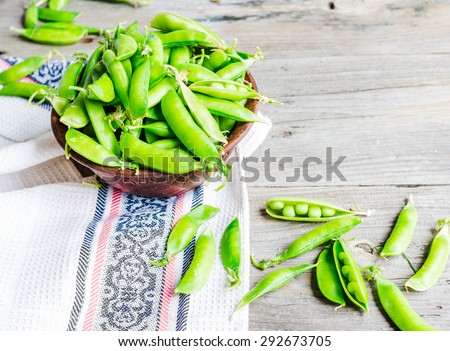 young green peas in the pod, earthenware dish, rustic background, raw,\clean eating, selective focus