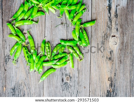 raw green peas in pods young on gray wooden background, rustic, healthy food, summer vegetables