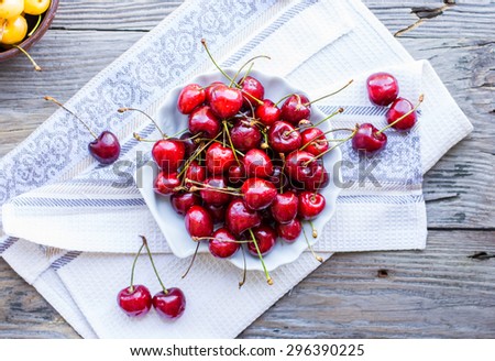 fresh red cherry in a plate on a gray wood background,\
healthy snack, summer berries, selective focus, top view