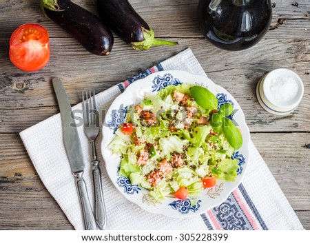 Fresh vegetable salad with tomato, eggplant, sesame seeds and flax, rustic background, top view