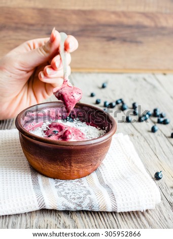 eating a banana ice cream with blueberries and coconut spoon, hand, healthy dessert, vegan, selective focus