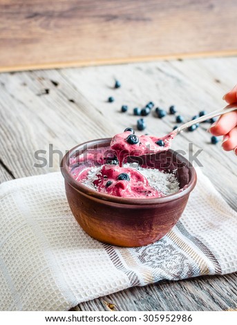 eating a banana ice cream with blueberries and coconut spoon, hand, healthy dessert, vegan,selective focus