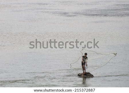 LUANG PRABANG, LAOS - JANUARY 15, 2011. Fisherman throwing his net in the Mekong river in Luang Prabang, Laos.