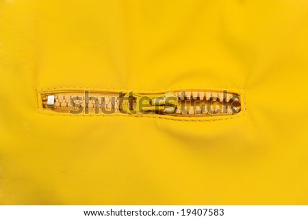 Closeup of a slightly open zipper (with bright yellow background)