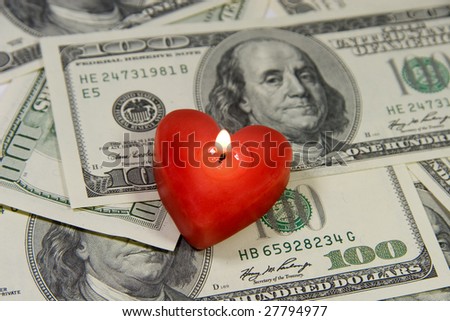 Red heart-shaped candle on a pile of US dollars (Love for Money concept)
