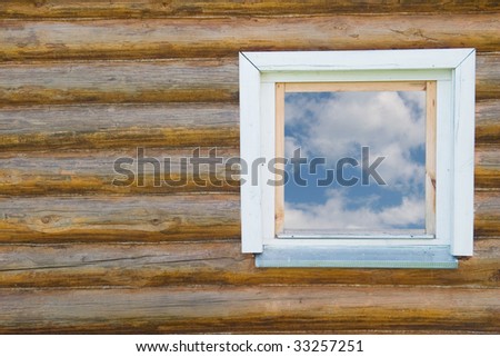 Old traditional country-style window in a wooden house (with the blue sky and white clouds in the window)
