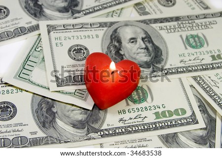 Red heart-shaped candle on a pile of US dollars (Love for Money concept)