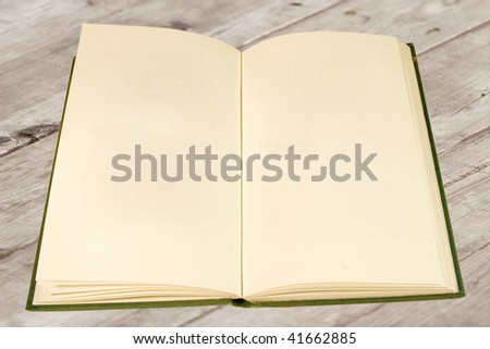 Open old book in green cover with blank pages (on a wooden surface)