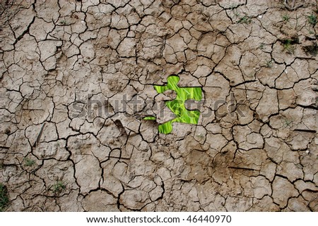 Cracked dry earth as a puzzle (with green grass as one piece)