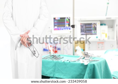 rear view image of doctors pose arms crossed behind back with stethoscope looking at medical equipment in a surgical room of modern hospital