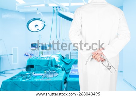 Close-up rear view image of doctors with stethoscope pose arms crossed behind back looking at medical equipment in a surgical room of modern hospital