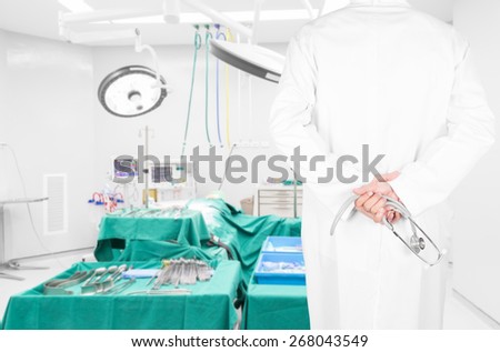 Close-up rear view image of doctors with stethoscope pose arms crossed behind back looking at medical equipment in a surgical room of modern hospital