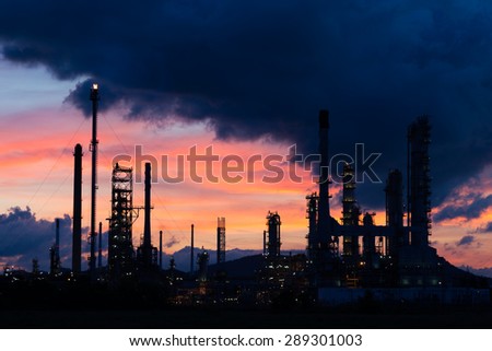 Oil refinery factory in silhouette at sunrise with dark cloud