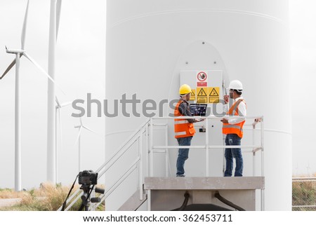 Electrical engineers and technician working in wind turbine power generator station with laptop computer