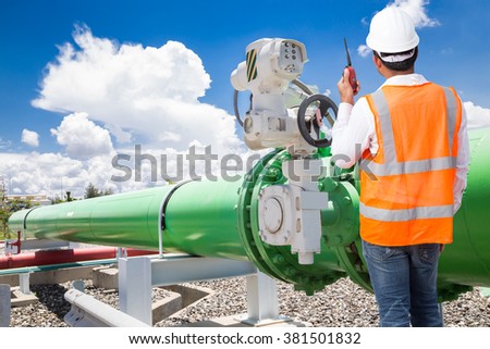 Engineer talking on the walkie-talkie for controlling pipeline valves of cooling water system at thermal power plant