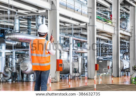 Engineer working in a thermal power plant with talking on the walkie-talkie for controlling work