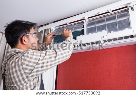 Young man electrician cleaning air conditioning in a client house