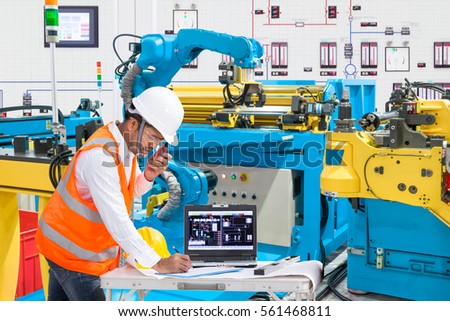 Engineer using laptop computer for maintenance automatic robotic hand machine tool at the factory