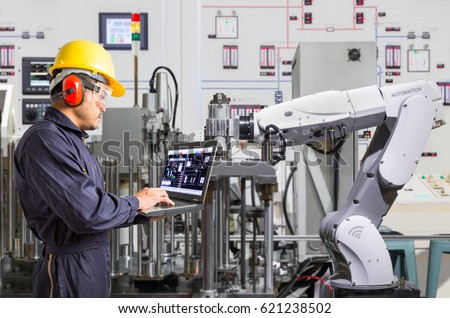 Engineer using laptop computer for maintenance automatic robotic hand machine tool in automotive industry