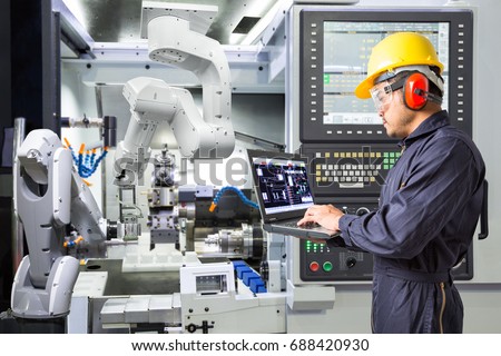 Engineer using laptop computer for maintenance automatic robotic industrial with CNC machine in smart factory. Industry 4.0 concept