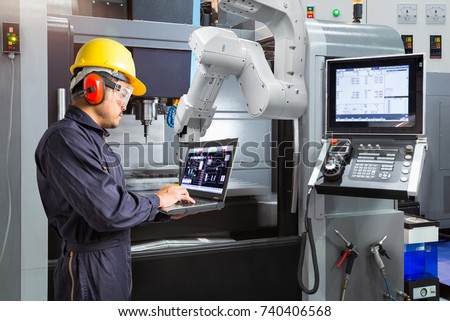 Maintenance engineer using laptop computer control automatic robotic hand with CNC machine in smart factory, Industry 4.0 concept