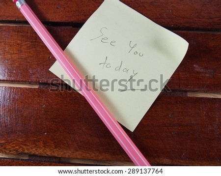 Reminder, see you today phrase on sticker paper with pink pencil on wood table background