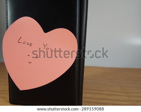 Love you writing, smiling face drawing on sticker paper with pink heart shape and skin cover of book