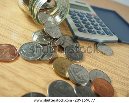 Saving money, pile of coins, Thai money in glassware, calculator on wood background